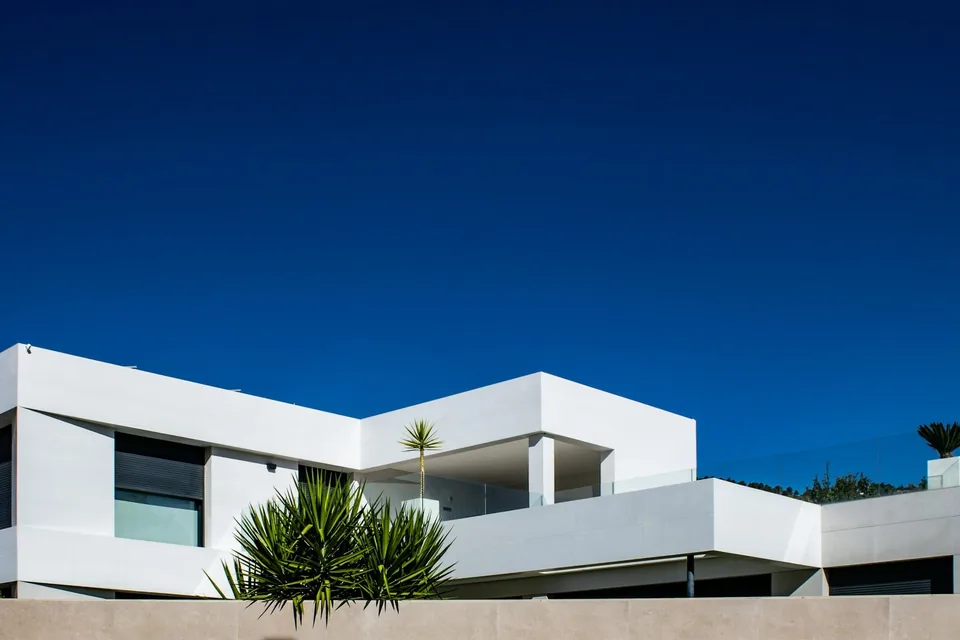 Casa moderna branca de linhas retas contra céu azul limpo.